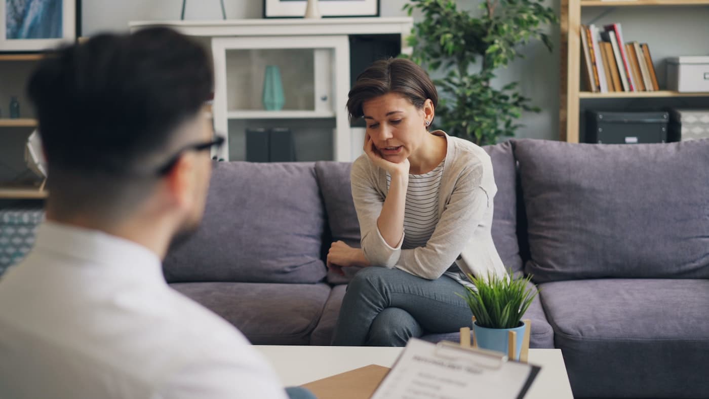 A visibly concerned woman speaking with an advisor who is listening and taking notes